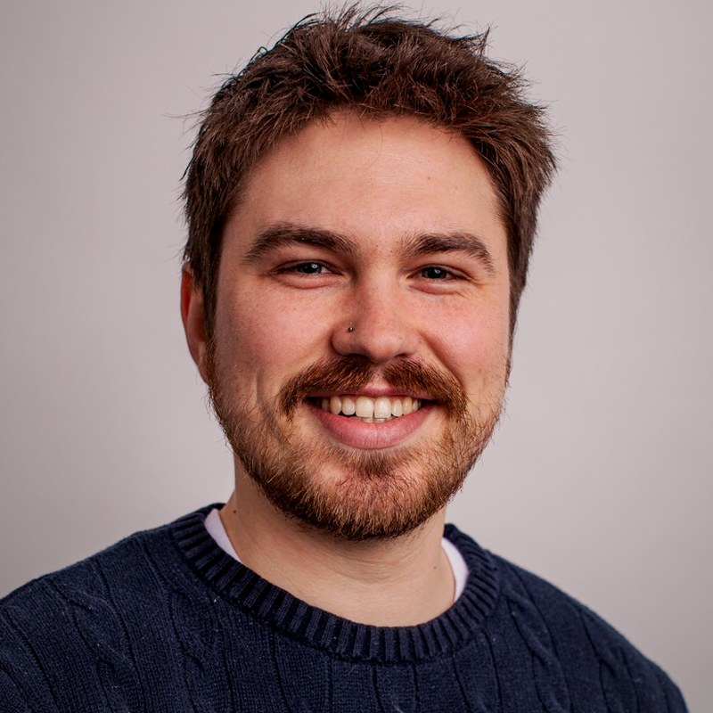 Ben Fox, smiling, in a navy cable-knit sweater
